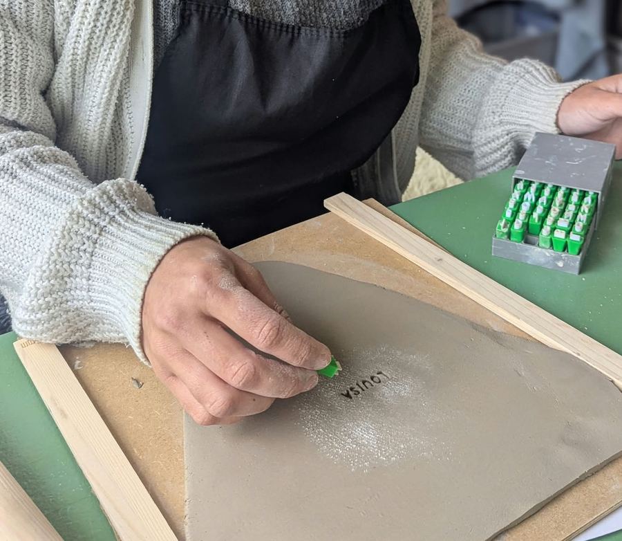 Name wird mit Buchstabenstempeln in Ton gedrückt